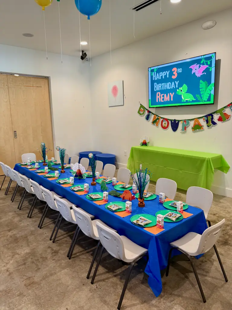 Dinosaur themed kids birthday party room at Ready Set FUN in Sandy Springs with decorated table, themed plates, centerpieces, and birthday banner