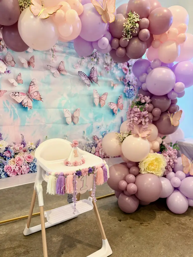 First birthday girl butterfly theme with floral balloon arch and decorated high chair at Ready Set Fun in Sandy Springs
