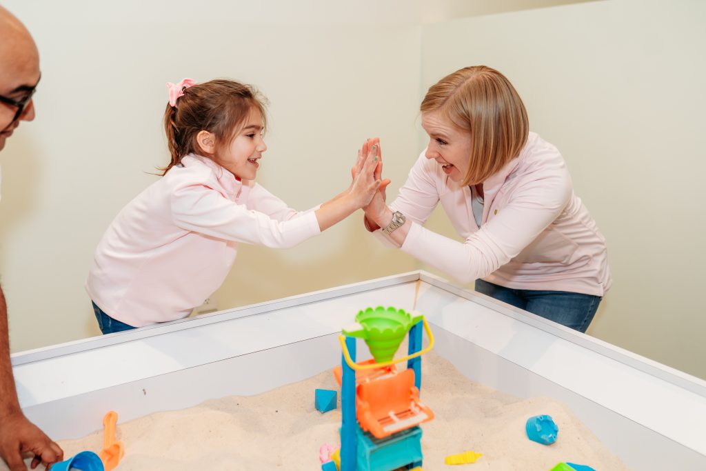 Parent and child playing together in sensory sandbox at Ready Set Fun indoor playground in Sandy Springs