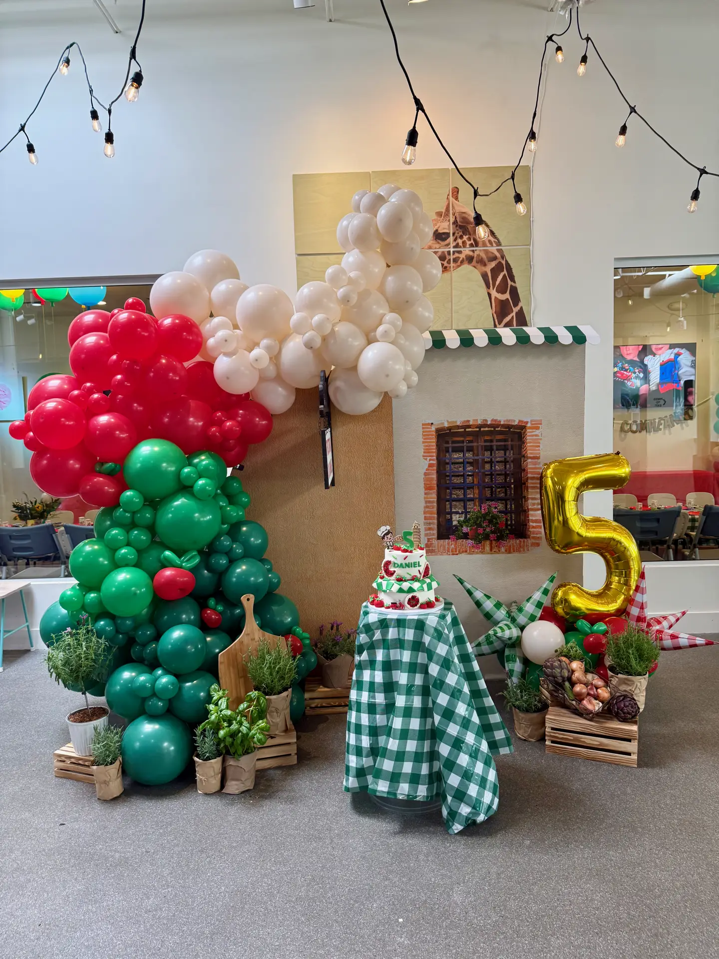 Fifth birthday boy Italian pizza chef theme with custom balloon cascade and backdrop and custom tiered cake at Ready Set Fun in Sandy Springs