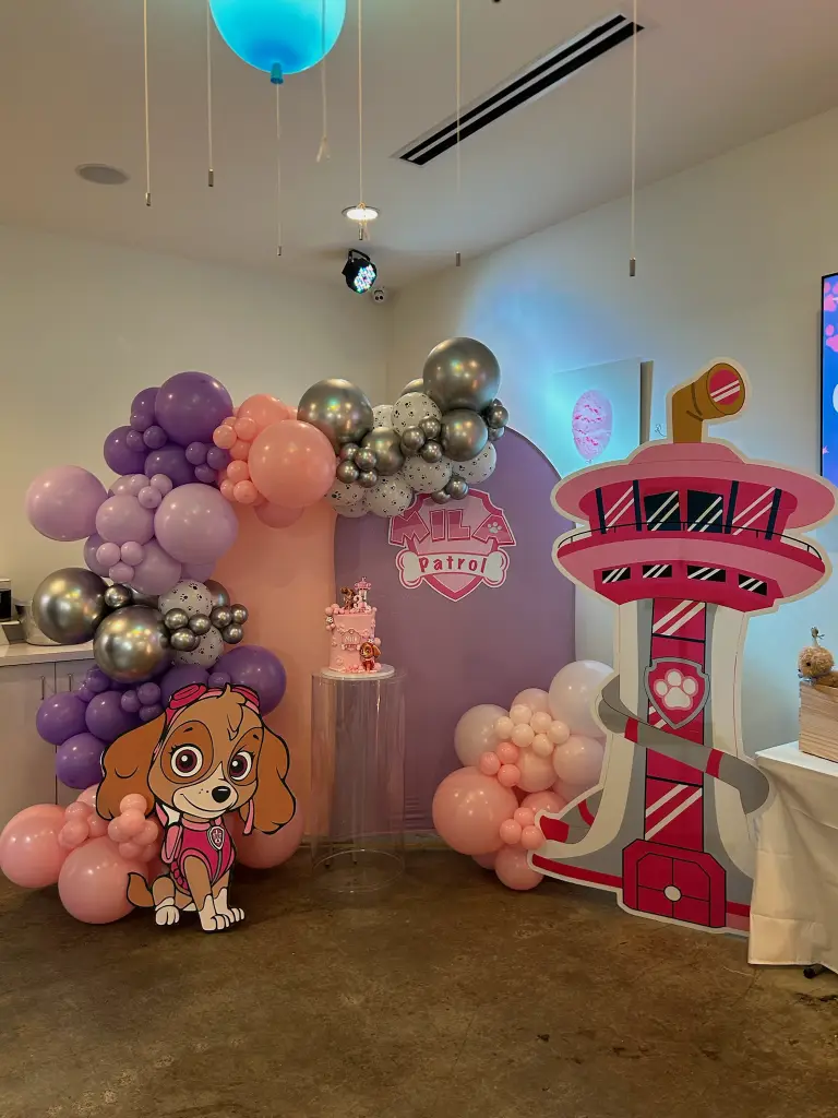 Paw Patrol Skye themed third birthday party with pink and purple organic balloon arch, custom backdrop, and character cutouts at Ready Set Fun in Sandy Springs