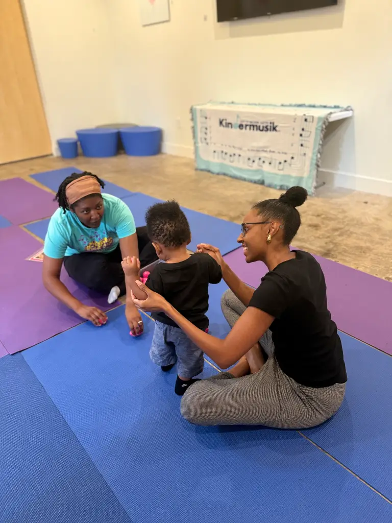 Mom helps her baby take steps toward an instructor during a Club Littles music class at Ready Set FUN in Sandy Springs