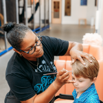 Boy getting his face painted at kids' birthday party at indoor playground