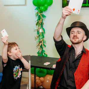 Magician shows his cards at a kids birthday party. Birthday boy is surprised the cards match.